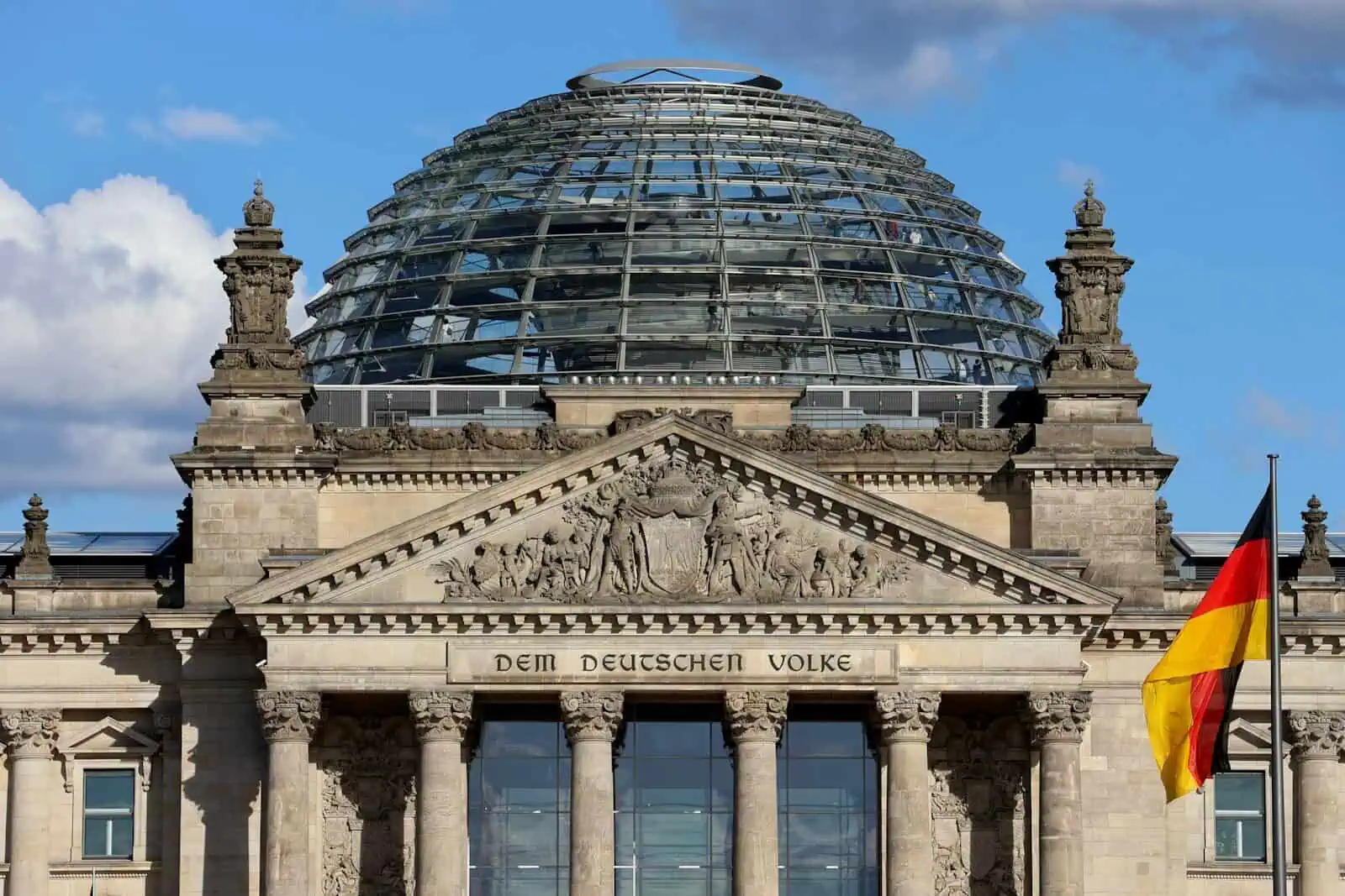 The reichstag building with glass dome and german flag.